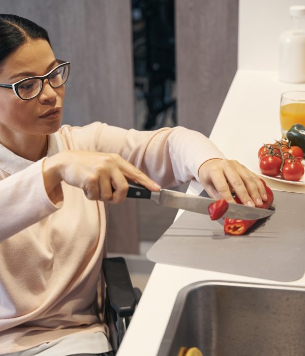 Elegant woman with disability making salad at home
