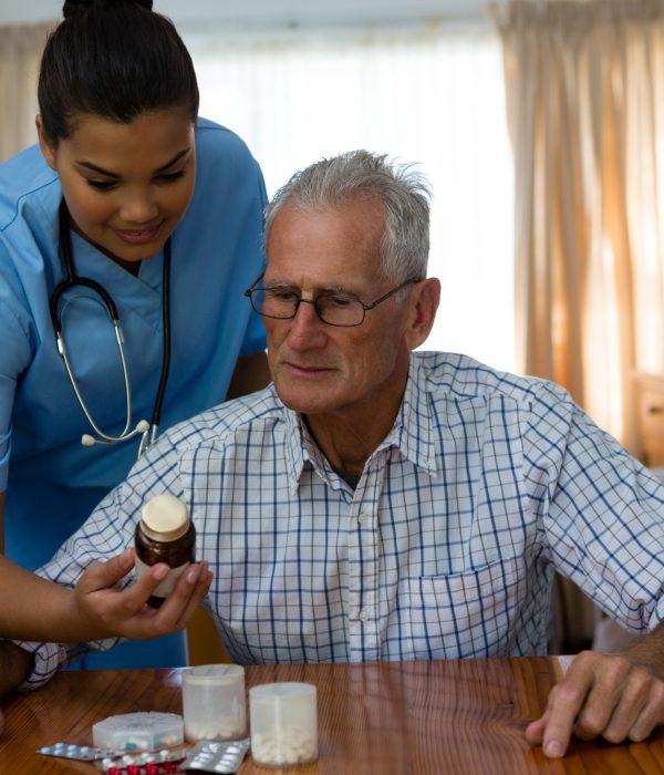 Female doctor assiting senior man in taking medicine