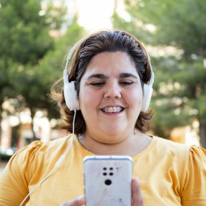Happy woman with intellectual disability listening to music outdoors