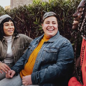 Interracial cheerful group of happy girls having fun talking together in the park talking and having fun sitting on a bench in the park